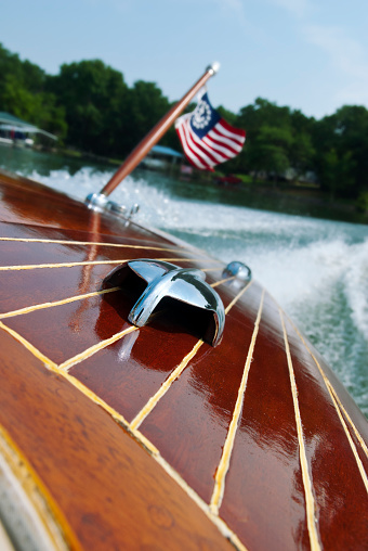 Perspective image of the stern of a vintage wooden motorboat with a patriotic flag