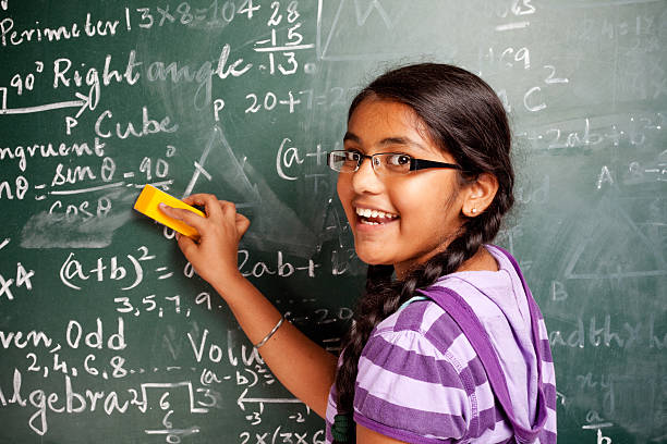 joyeuse fille d'étudiant indien effaçant mathématiques problèmes de greenboard tableau noir - indian girls photos et images de collection