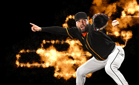 Baseball player with bat taking a swing on grand arena. Ballplayer on dark background in action. Sports cover or wallpaper.