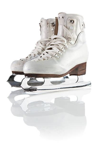 Figure skates hanging frm an old fashioned coat peg on a red wall background.