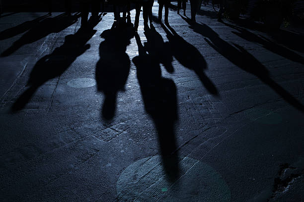 Gang of people advancing on viewer blue night shadows stock photo