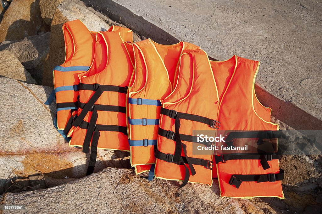 Arancio giubbotti di salvataggio su sfondo di pietre - Foto stock royalty-free di Gilet - Capo di vestiario