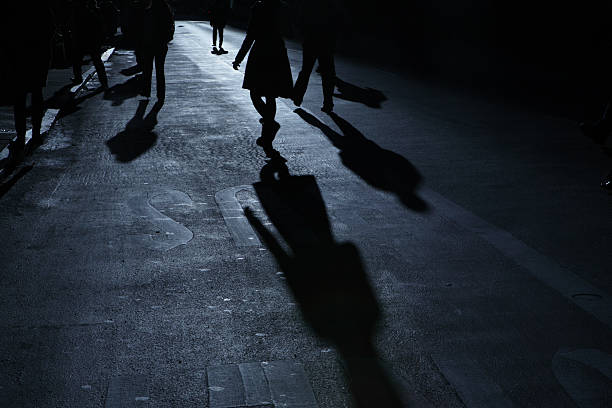 istock Group of people walking down a road in night shadows 183776047