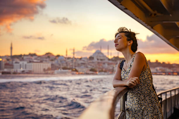 Tourist young lady is traveling around city of Istanbul. Young woman is traveling around city of Istanbul with ferry at sunset. berk stock pictures, royalty-free photos & images