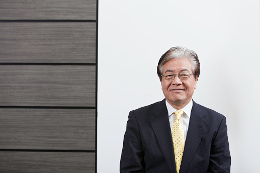 Smiling Asian business man in front of simple background