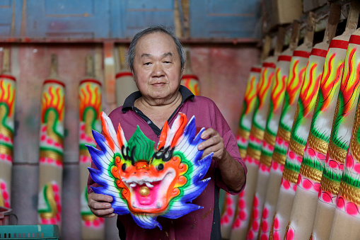 An Asian senior man is showing Dragon Sculpture Joss stick in factory