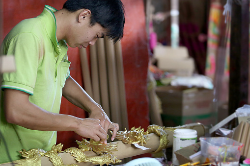 An Asian man is working in Dragon Sculpture Joss stick factory