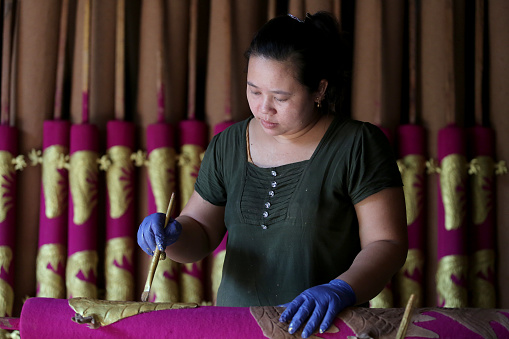 A Myanmar woman is painting gold in Dragon Sculpture Joss stick factory daily production