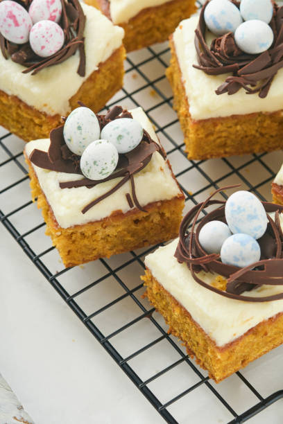 istock Easter carrot cake bars decorated with chocolate nest and chocolate candy eggs blossoming cherry or apple flowers on rustic light wooden backgrounds. Easter holiday meal. Traditional Easter food. 1837792420