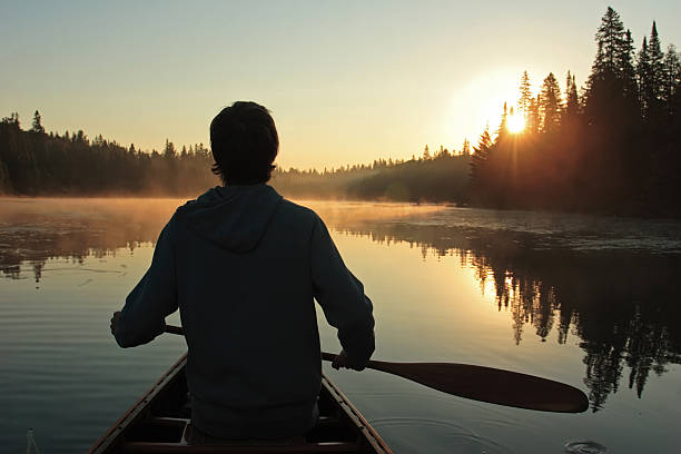 alba a paletta - men sitting canoe canoeing foto e immagini stock