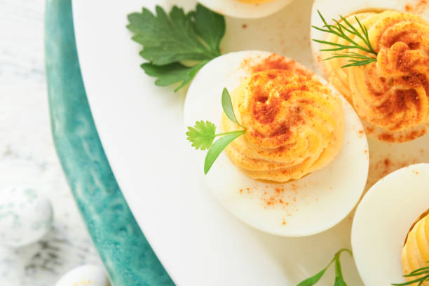 istock Easter stuffed eggs. Traditional Easter brunch or dinner with stuffed eggs with paprika, carrot cake bars and chocolate nest cakes with glazed eggs. Easter meal dishes with holday decorations Top view 1837794850