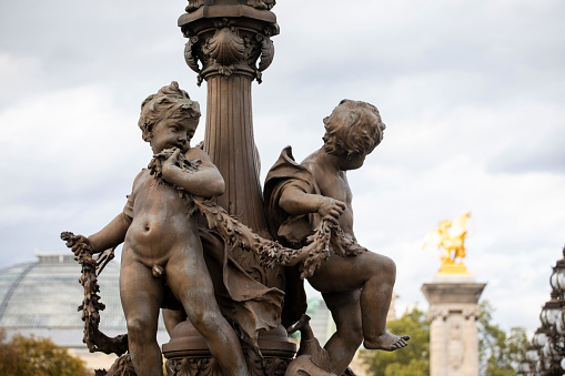 Human figure sculptures at the base of the lamp posts on Pont Alexandre III