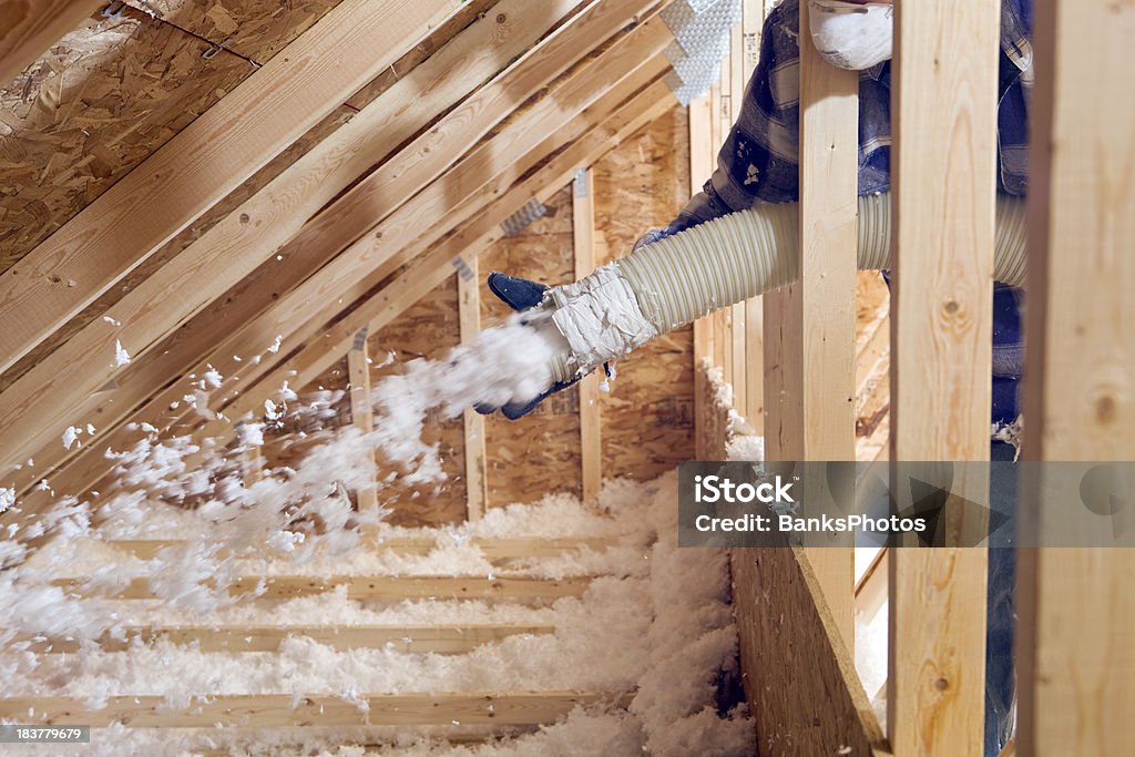 Worker Spraying Blown Fiberglass Insulation between Attic Trusses  Insulation Stock Photo