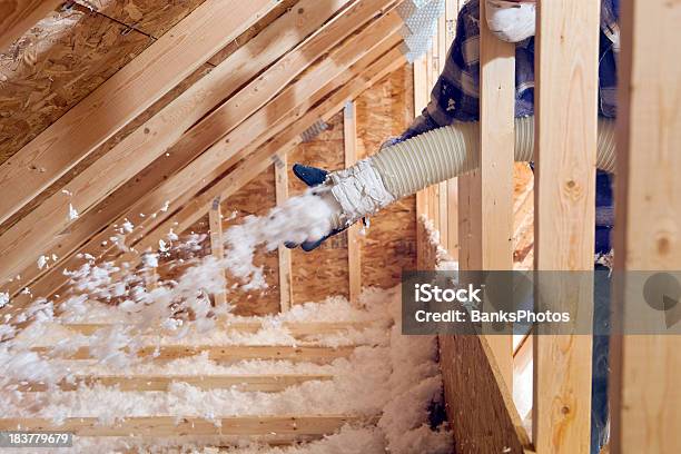 Worker Spraying Blown Fiberglass Insulation Between Attic Trusses Stock Photo - Download Image Now
