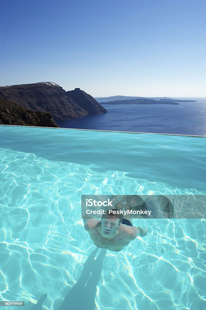 Uomo nuota sott'acqua in piscina a sfioro con vista spettacolare - Foto stock royalty-free di Acqua