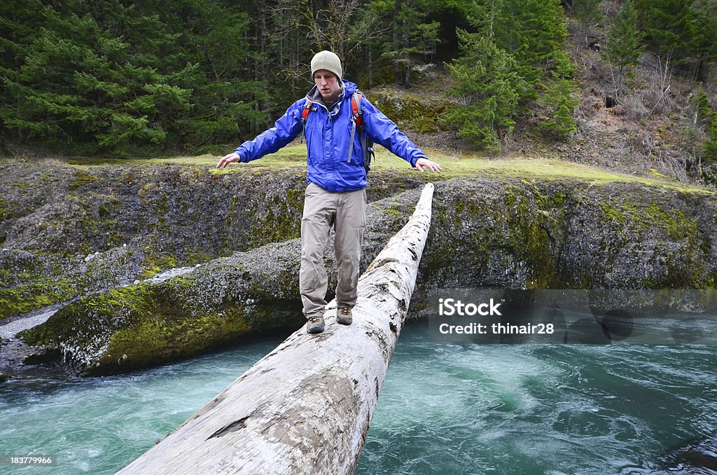 Hiker crossing log "A hiker crosses a narrow log high over a swirling river. Clackamas River, Oregon.See also these similar images:" 20-29 Years Stock Photo