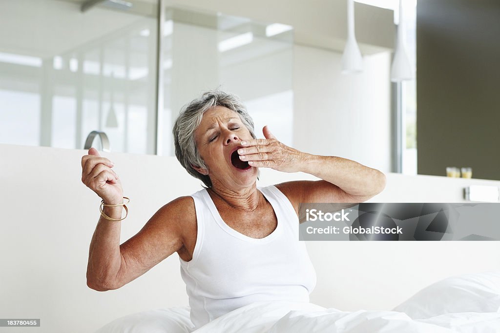 Senior femme bâillement au lit - Photo de Bâiller libre de droits