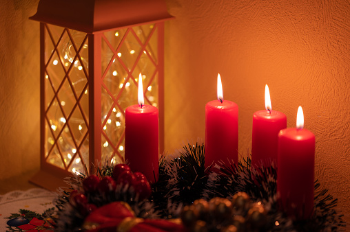 Christmas candles and snowy fir branches over white wooden background with lights