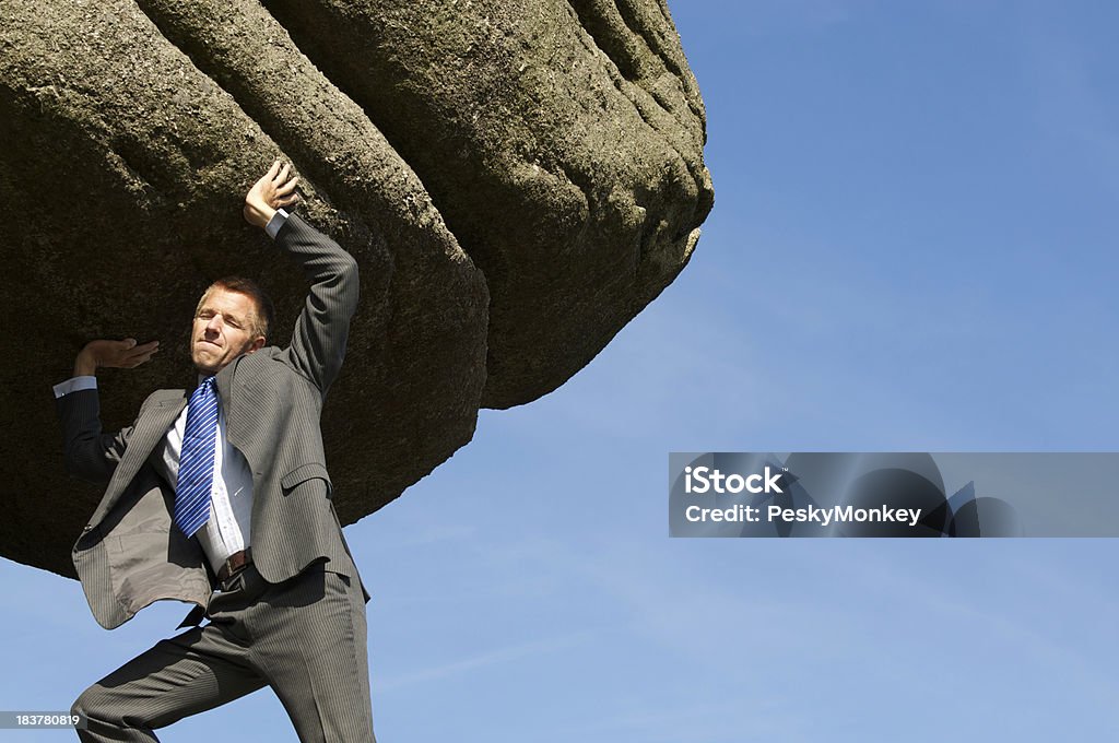 Homme d'affaires a des difficultés Heaving énorme rocher Boulder dans le ciel - Photo de Roc libre de droits