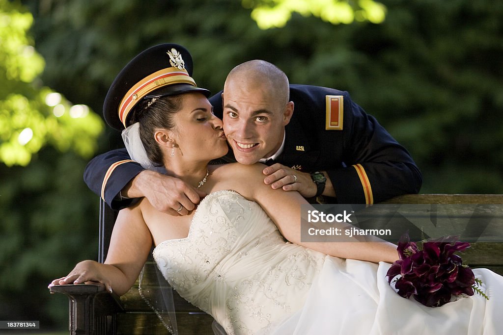 新婦様のウェディングドレス花婿マリーヌ均一な公園のベンチにキスをする - ウェディングドレスのロイヤリティフリーストックフォト