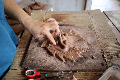 Asian female working in sculpting joss stick factory.