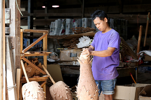 Asian male working in sculpting pineapple shaped joss stick factory.