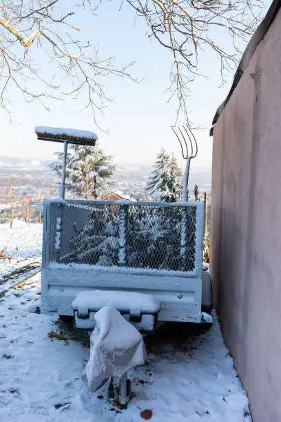 Photo of Gardening tools stick out of the trailer covered in snow.