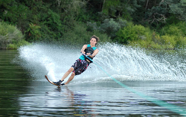 young man kicking up spray on water ski stock photo