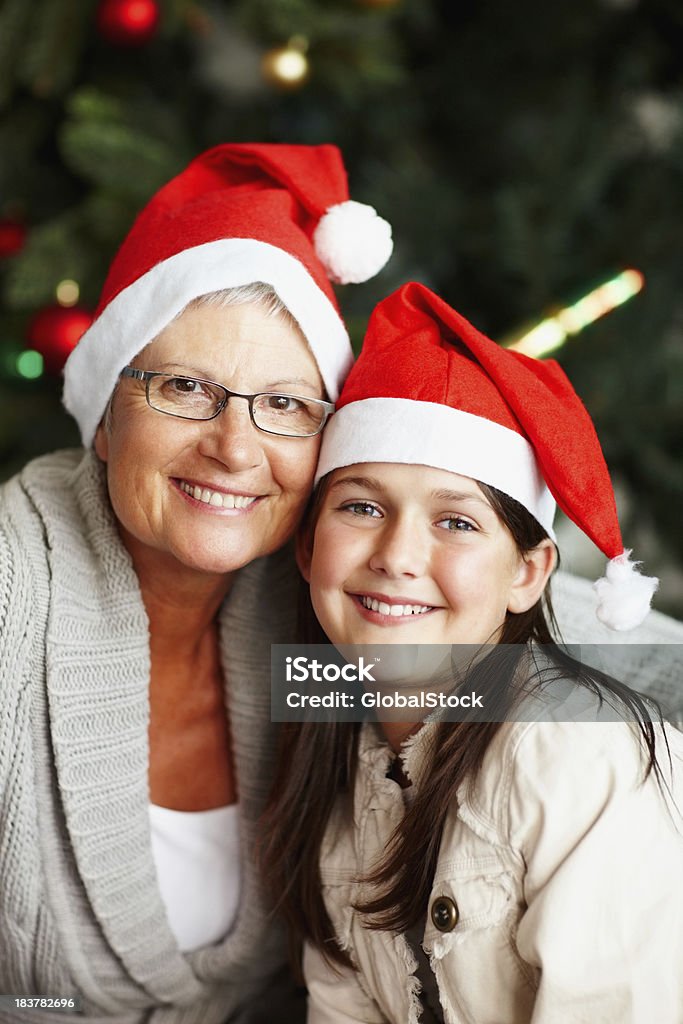 Grandmother and granddaughter celebrating Christmas Grandmother and granddaughter wearing Santa's cap and smiling 50-59 Years Stock Photo