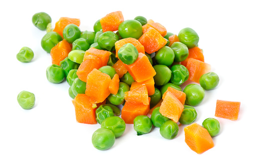 Macro pile of peas and carrots on white.