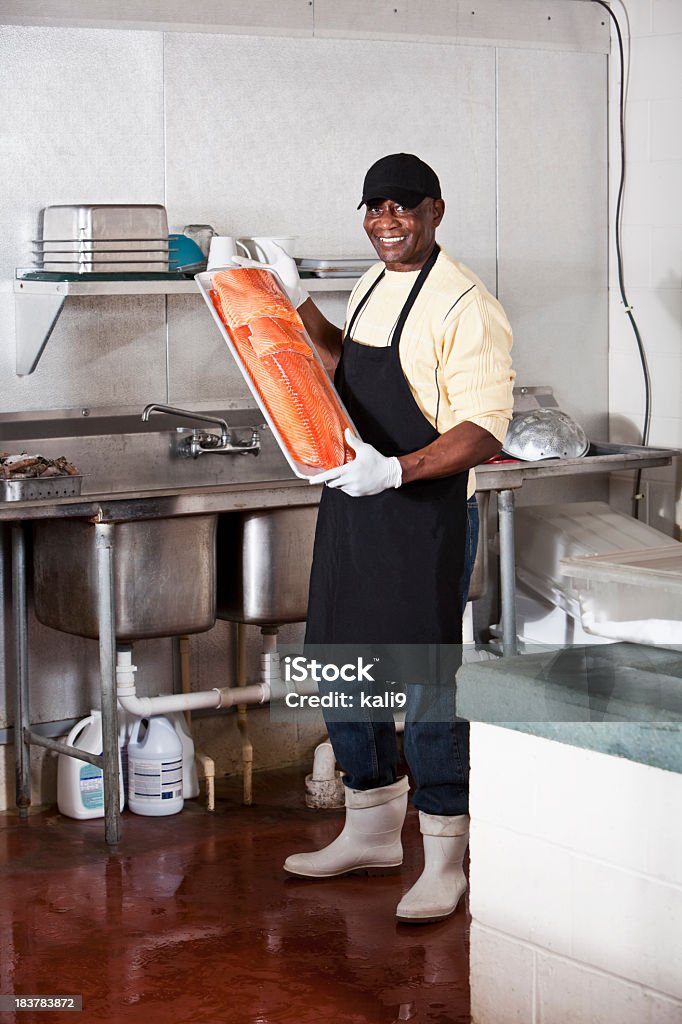 Uomo che lavora in Sala posteriore di mercato del pesce - Foto stock royalty-free di 60-64 anni