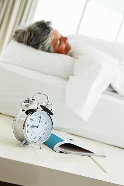 istock Senior woman sleeping with her alarm clock nearby 183784012