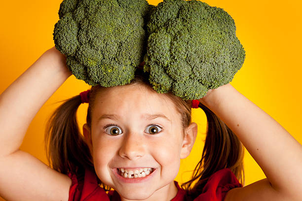 istock Happy Young Girl Holding Broccoli and Smiling 183784299