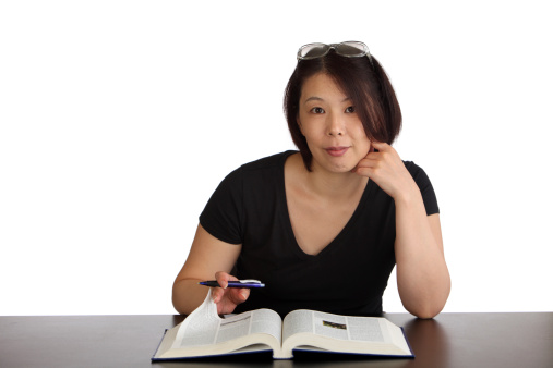 Japanese woman at a desk with textbook and pen. White background.