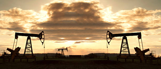 Oil rig at sunset the sun. Silhouette of Pump Jack are running. stock photo