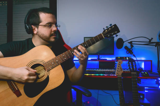 portret latynoskiego gitarzysty muzyki klasycznej, siedzącego w swoim domowym studiu i grającego na gitarze - contreras zdjęcia i obrazy z banku zdjęć