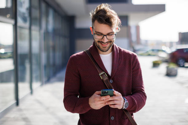 istock Smiling young man using mobile phone outdoors 1837914351