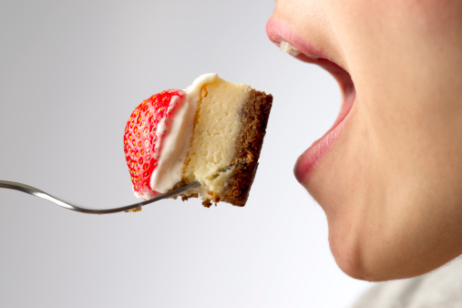 Close-up of female mouth about to eat a chunk of cheesecake with strawberry. XXXL.Click to see more food shots: