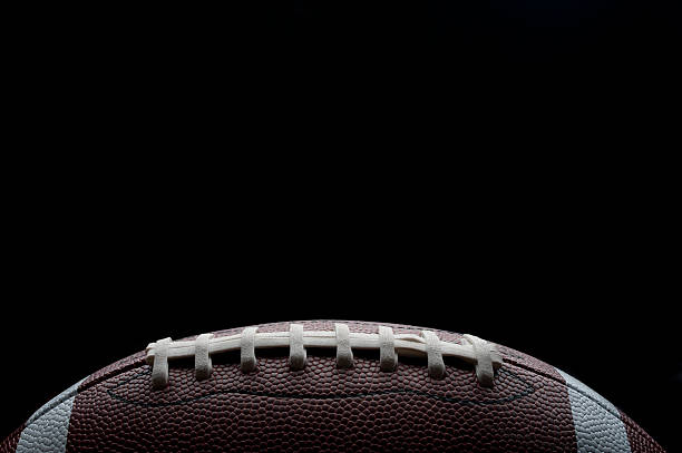 Stylish shot of a gridiron football Stylish shot of a gridiron football on a black background pigskin stock pictures, royalty-free photos & images