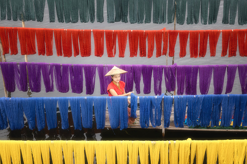 A woman is drying cotton fabrics in sunlight after natural dye is a dying trait in Inle Lake,Handcrafted fabrics are very traditional and popular in Inle Lake main materials is a stem of lotus flowers that the local people they harvest from the lake,Shan State,Myanmar.