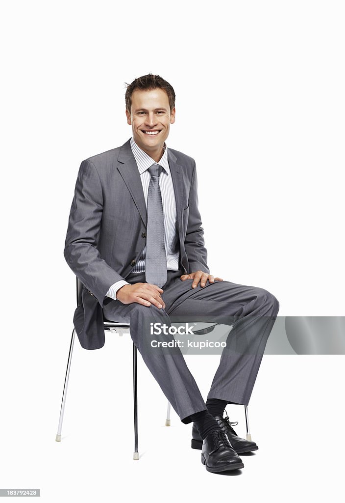 Uomo d'affari seduto su una sedia sorridente - Foto stock royalty-free di Completo
