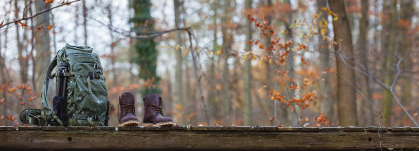 Hiking equipment in forest. Backpack with tripod and leather ankle boots
