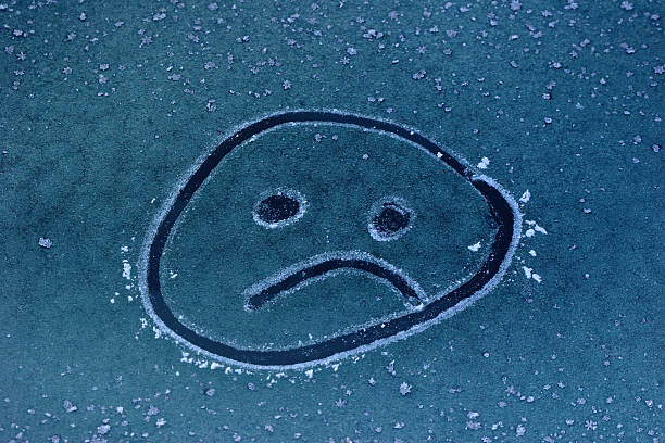 Winter Frowing Face An unhappy frowning face drawn on an ice covered car window. seasonal affective disorder stock pictures, royalty-free photos & images