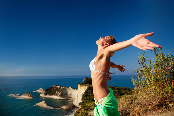 Woman standing on rock with arms outstretched stock photo