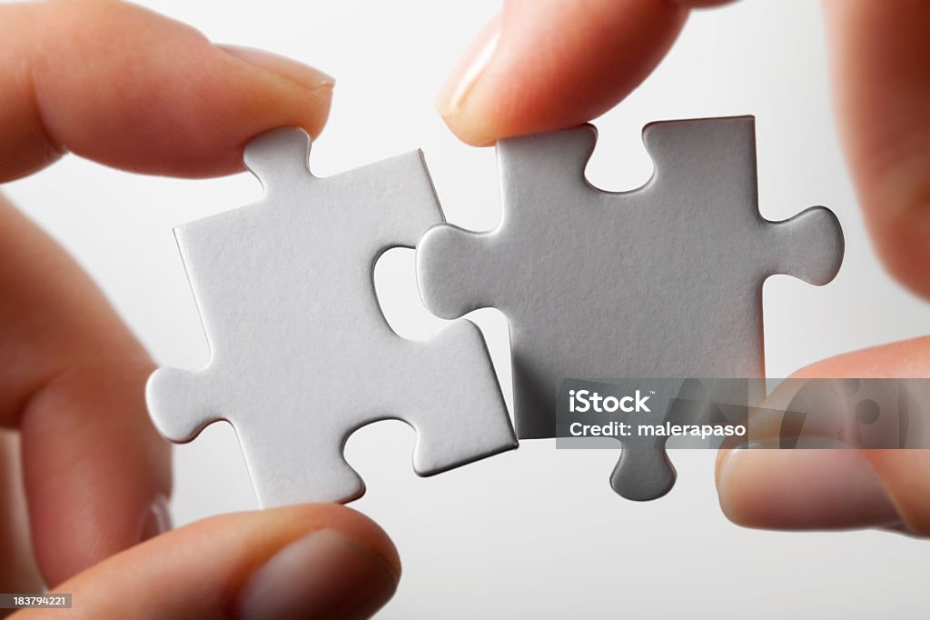Connection. Hands trying to fit two puzzle pieces together. Hands trying to fit two puzzle pieces together. Two Objects Stock Photo