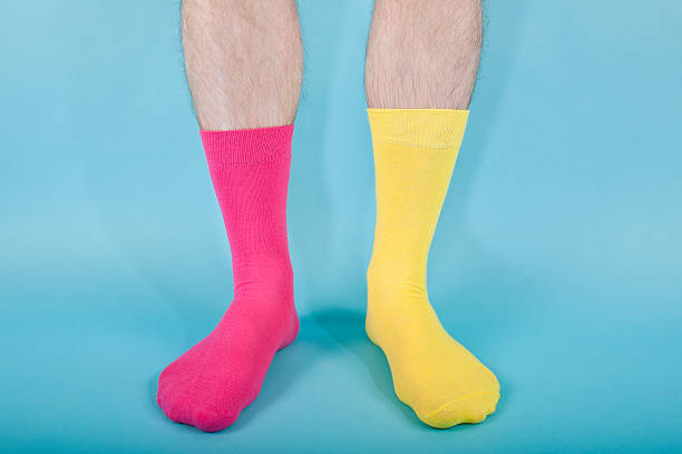 Odd socks "Man standing against a blue background wearing bright coloured odd socks.Concepts, clashing, difference, wrong, etc" pair stock pictures, royalty-free photos & images