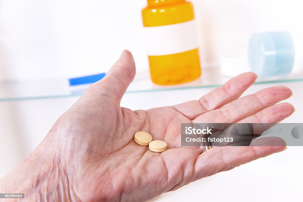 Donna Senior con pillole farmaco nella parte anteriore del cabinet. - Foto stock royalty-free di Armadietto del bagno