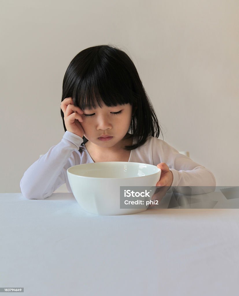Young Asian Girl Doesn't Like Her Food An Unhappy Young Asian Girl's Staring at Her Meal in a big White Bowl but doesn't want to eat it. Girl with no appetite. Model positioned in the center of Vertical Format Beige Color Background. Please check out more of my stock photos and illustrations at: http://www.istockphoto.com/portfolio/phi2. No Appetite Stock Photo
