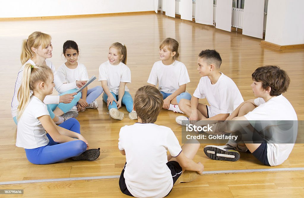 Equipo de deportes para niños hablando y hembra entrenador en el gimnasio. - Foto de stock de 10-11 años libre de derechos