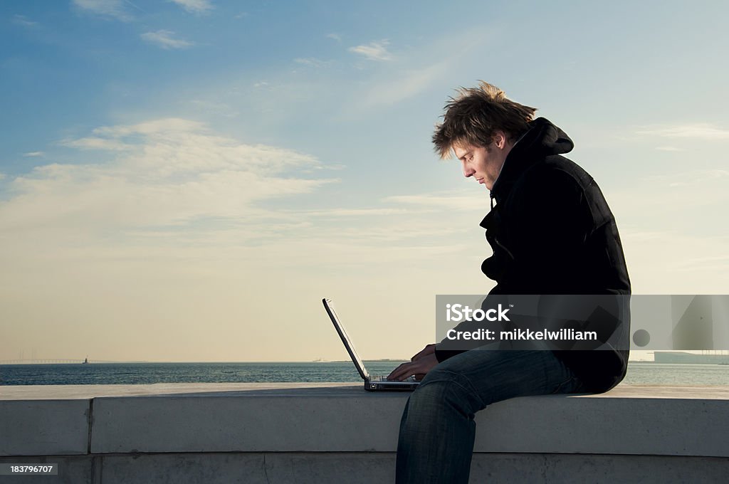 Uomo funziona sul computer portatile da vicino il mare - Foto stock royalty-free di Computer portatile